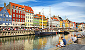 Turists resting at Nyhavn Canal, Copenhagen, Denmark.