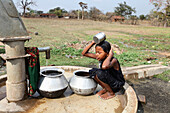 Tribal girl taking bath on a handpump, Baiga tribe. Karangra Village, Chhattisgarh, India.
