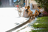 Teenage girls cooling their feet in a stream, Freiburg im Breisgau, Black Forest, Baden-Wuerttemberg, Germany