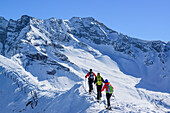 Three persons back-country skiing ascending on snow-ridge, Zillertal Alps in background, Gammerspitze, valley of Schmirn, Zillertal Alps, Tyrol, Austria