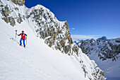 Woman back-country skiing ascending to La Forcellina, Monte Oronaye in the background, Col Sautron, Valle Maira, Cottian Alps, Piedmont, Italy