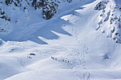 Several persons back-country skiing ascending to Passo Croce, Passo Croce, Valle Maira, Cottian Alps, Piedmont, Italy