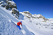 Woman back-country skiing downhill through powder snow from Passo Croce, Passo Croce, Valle Maira, Cottian Alps, Piedmont, Italy