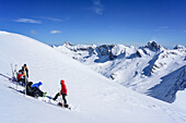 Mehrere Personen auf Skitour machen am Monte Faraut Pause, Pelvo d'Elva und Rocca la Marchisa im Hintergrund, Monte Faraut, Valle Varaita, Cottische Alpen, Piemont, Italien