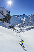 Woman back-country skiing ascending towards Monte Salza, in the background Rocca Senghi, Monte Salza, Valle Varaita, Cottian Alps, Piedmont, Italy