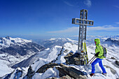 Frau auf Skitour steht am Gipfelkreuz des Monte Salza, Monte Salza, Valle Varaita, Cottische Alpen, Piemont, Italien