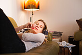 Junge Frau zuhause, entspannt sich auf dem Sofa, innenaufnahme