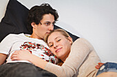 Young couple at home, cuddling on the sofa