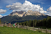 zwei Mountainbikerinnen bei Deutschnofen, dahinter der Gebirgsstock Latemar, Trentino, Italien