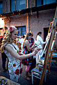Young women painting in front of the studio of artist Patricia Peatten, near the harbour, Andrejostas Iela 4, Riga, Latvia