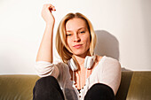 Young woman sitting on the sofa, daydreaming