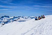 Several persons back-country skiing having a break at summit of Palon de la Mare, Presanella and Adamello in the background, Palon de la Mare, Val dei Forni, Ortler range, Lombardy, Italy