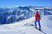 Woman back-country skiing looking towards Pelvo d'Elva, Rocca La Marchisa, Tete de Moise and Monte Faraut, Punta Tre Chiosis, Valle Varaita, Cottian Alps, Piedmont, Italy
