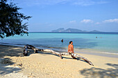 Woman sat on driftwood on the beach, Island Kradan, Andaman Sea, south- Thailand, Thailand, Asia