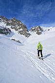 Woman back-country skiing ascending towards Colle d'Enchiausa, view to Monte Oronaye, Valle Enchiausa, Valle Maira, Cottian Alps, Piedmont, Italy