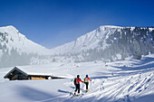 Two persons back-country skiing ascending past alpine hut towards Sonntagshorn, Sonntagshorn, Chiemgau range, Salzburg, Austria