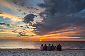 Familie sitz am Strand und genießt den Sonnenuntergang, Ahrenshoop, Mecklenburg Vorpommern, Deutschland