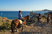 Tourists on horseback, horse riding from San Jose on the rocky coast of Cabo de Gata in the afternoon, Almeria province, Andalusia, Spain