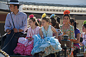 Kutsche mit Kindern und junger Frau in Flamenco Kleidern, Pilger bei der Wallfahrt zu Pfingsten zu 'Nuestra Senora de El Rocio' an der Kirche, El Rocio, Huelva, Andalusien, Spanien