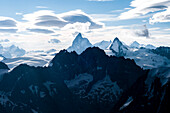 In der Mitte das Matterhorn von Westen, rechts davon die Dent d'Hérens, dahinter die Gipfel des Monte Rosa, im Vordergrund dunkel die Bouquetins, im Himmel Föhnwolken, Walliser Alpen, Kanton Wallis, Schweiz