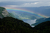 Ein Regenbogen über dem Bohinjsee respektive Wocheinersee, darunter das Dorf Stara Fužina, Triglav Nationalpark, Julische Alpen, Slowenien