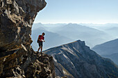 A young alpine hiker looking for a possible scrambling route to reach the summit of Felsberger Calanda, massif of Calanda, Grison Alps, cantons of Grison and St. Gallen, Switzerland
