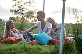 Young people having a picnic in a green field, Krautinsel, Chiemsee, Bavaria, Germany