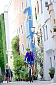 Fahrradfahrerin fährt durch Altstadt, Burghausen, Chiemgau, Bayern, Deutschland