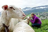 Frau streichelt ein Schaf, Chiemgau, Bayern, Deutschland