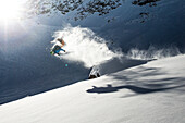 Junger Skifahrer macht einen Backflip über einen Felsen, Pitztal, Tirol, Österreich