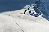 Three people hiking up a mountain with skis, Pitztal, Tyrol, Austria