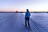 Junge Frau geht Langlaufen während eines Sonnenuntergangs, Allgäu, Bayern, Deutschland