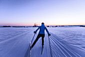Young woman cross-country skiing at sunset, Allgaeu, Bavaria, Germany