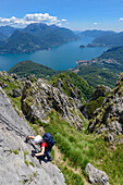 Frau im Klettersteig Via Ferrata del Centenario vor Menaggio rechten Ufer des Comer Sees und Grigna Settentrionale (2408 m) darüber, Lombardei, Italien