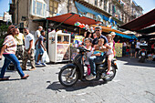 Mann und drei Kinder fahren auf einem Aprilia Roller vor dem Ballaro Markt, Palermo, Sizilien, Italien, Europa