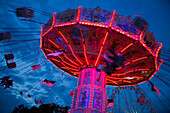 People enjoy carousel ride at Bayreuther Volksfest beerfest and amusement park at dusk, Bayreuth, Franconia, Bavaria, Germany