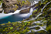 Wasserfall fließt über bemooste Felsen in der Schlucht Gjáin, Gjárfoss Wasserfälle mit Fluss Rauda, Ãžjorsardalur Tal, Südisland, Island