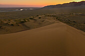 Blick von der Singenden Düne auf Ili-Flusstal und die Berge des Dsungarischen Alatau zu Sonnenuntergang, Wüste im Altyn Emel Nationalpark, Region Almaty, Kasachstan, Zentralasien, Asien