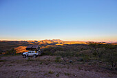 Off-road vehicle with roof top tent in sunrise, Gamsberg pass, Namibia