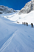 Backcountry skiers and snowboaders ascending Sonntagskogel peak, Tennengebirge mountains, Salzburg, Austria