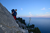 A young woman hiking along the mountainous coast at dusk, Selvaggio Blu, Sardinia, Italy, Europe