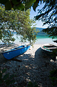 Fishing boats on the shore of lake Walchensee with view towards Sassau island, Walchensee, Bavaria, Germany