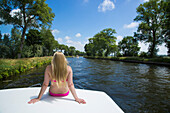 Junge blonde Frau im Bikini entspannt sich auf dem Sonnendeck von einem Hausboot auf dem Kanal Plassendale - Niuewpoort, nahe Brügge, Flandern, Belgien, Europa