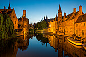 Spiegelung von Belfried und angeleuchteten Gebäuden in einem Kanal in der historischen Altstadt in der Dämmerung, Brügge, Flandern, Belgien, Europa
