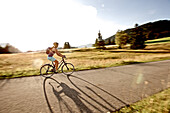 Junge Frau fährt Fahrrad an einem sonnigen Tag, Tannheimer Tal, Tirol, Österreich