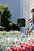 Young woman pushing her bike through a park,  Kempten, Bavaria, Germany