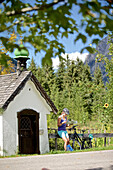 Young female cyclist having a break to read a map / Tannheimer Tal, Tyrol, Austria
