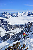Woman back-country skiing descending ridge from Aeusserer Baerenbartkogel, Aeusserer Baerenbartkogel, valley of Langtaufers, Vinschgau, Oetztal Alps, South Tyrol, Italy