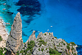 Blick von Punta Salinas auf Felsturm und Boote in Cala Goloritze am Mittelmeer, Punta Salinas, Selvaggio Blu, Nationalpark Golfo di Orosei e del Gennargentu, Sardinien, Italien