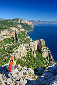 Frau sitzt am Selvaggio Blu und blickt auf Mittelmeer, Selvaggio Blu, Nationalpark Golfo di Orosei e del Gennargentu, Sardinien, Italien